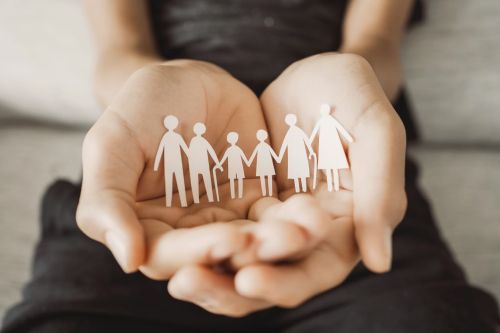 Hands holding paper cutout multi generation family concept for an estate planning blog discussing tips for talking to your family about your estate plan.