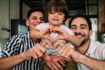 Happy gay couple posing with their son while making a heart shape with their hands showing love. Family concept for an estate planning blog discussing lgbtq+ estate planning.