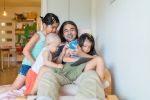 father sitting in chair with three young children